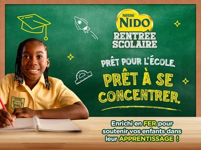Une écolière souriante assise à son bureau, un cahier ouvert devant elle, sur fond vert, avec le logo NIDO.